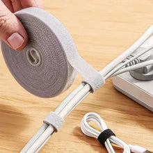 Person holding a roll of cable tie with white cables on a wooden surface