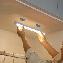 Person installing a LED strip light under a cabinet.