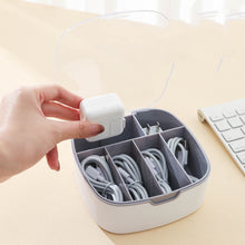 Hand placing a white electronic device into a cable organizer on a desk.